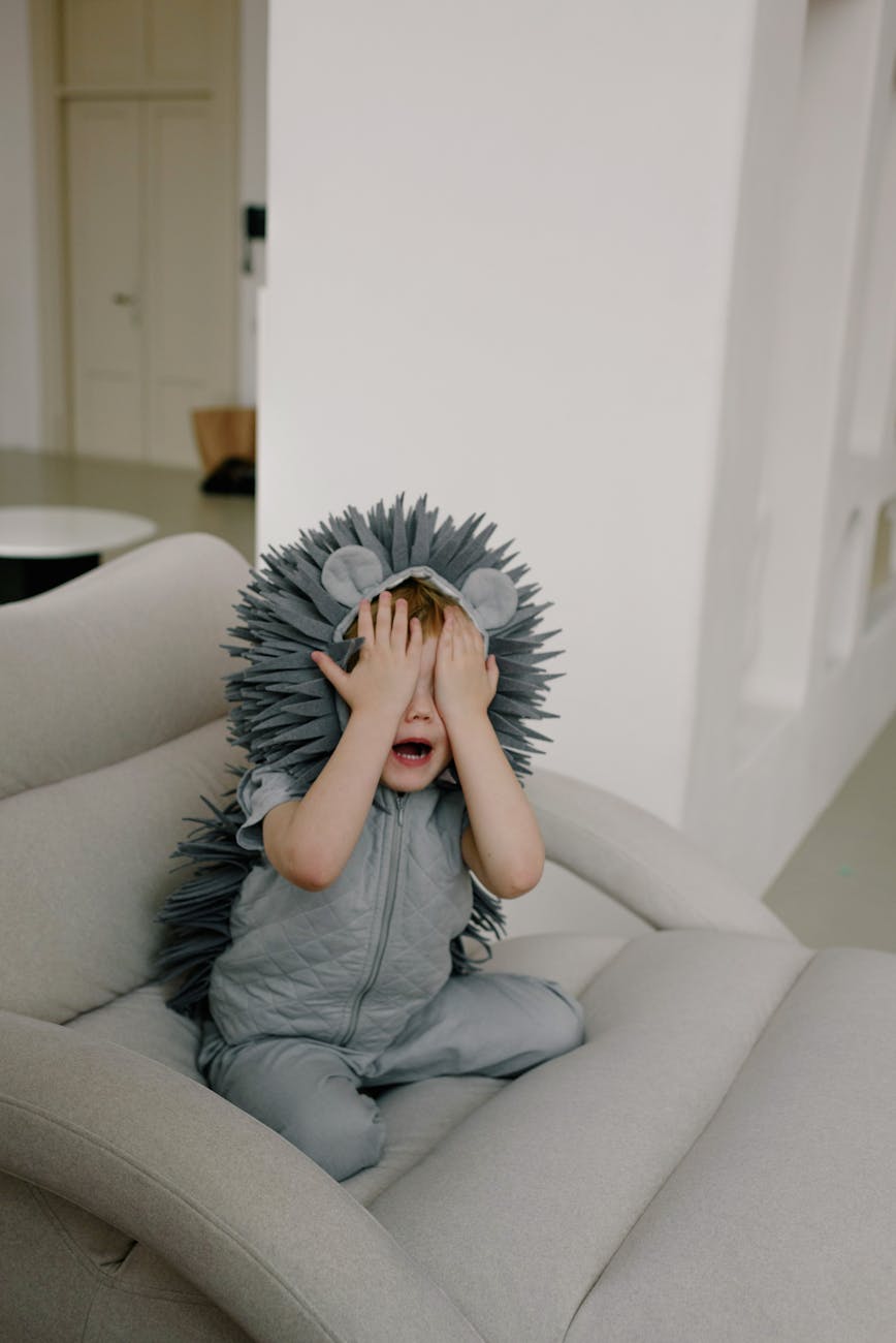 a boy wearing costume covering his eyes